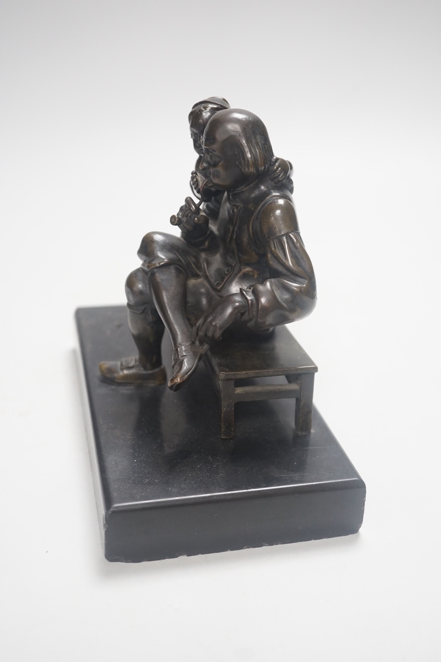 A 19th century bronze group of a gentleman smoking a pipe and a girl, on slate base 18.5cm wide